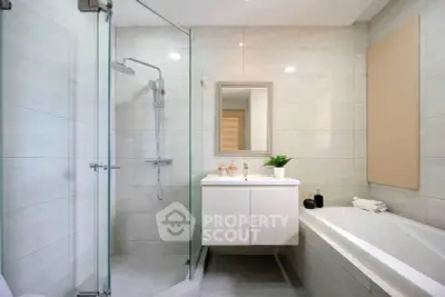 Modern bathroom with glass shower, bathtub, and sleek vanity in a contemporary home.