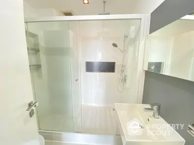 Sleek modern bathroom with glass-enclosed shower, white vanity, and stylish fixtures, perfect for a contemporary home.