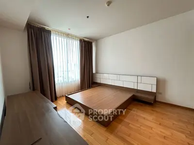 Spacious bedroom with wooden flooring and large window in modern apartment