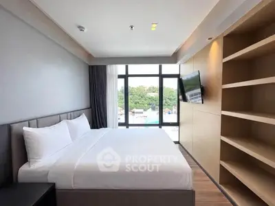 Modern bedroom with large window and built-in shelves, offering a serene view.