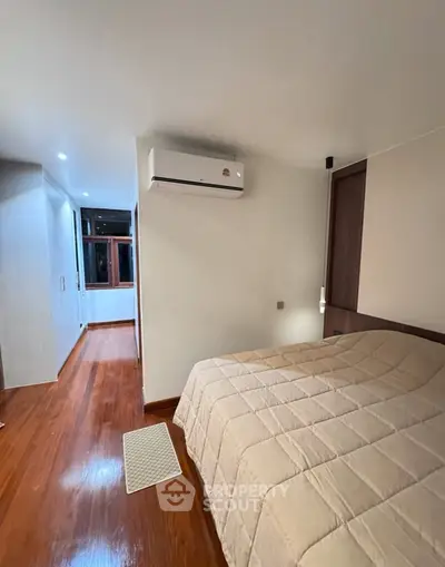 Cozy bedroom with wooden flooring and air conditioning, perfect for comfort and relaxation.