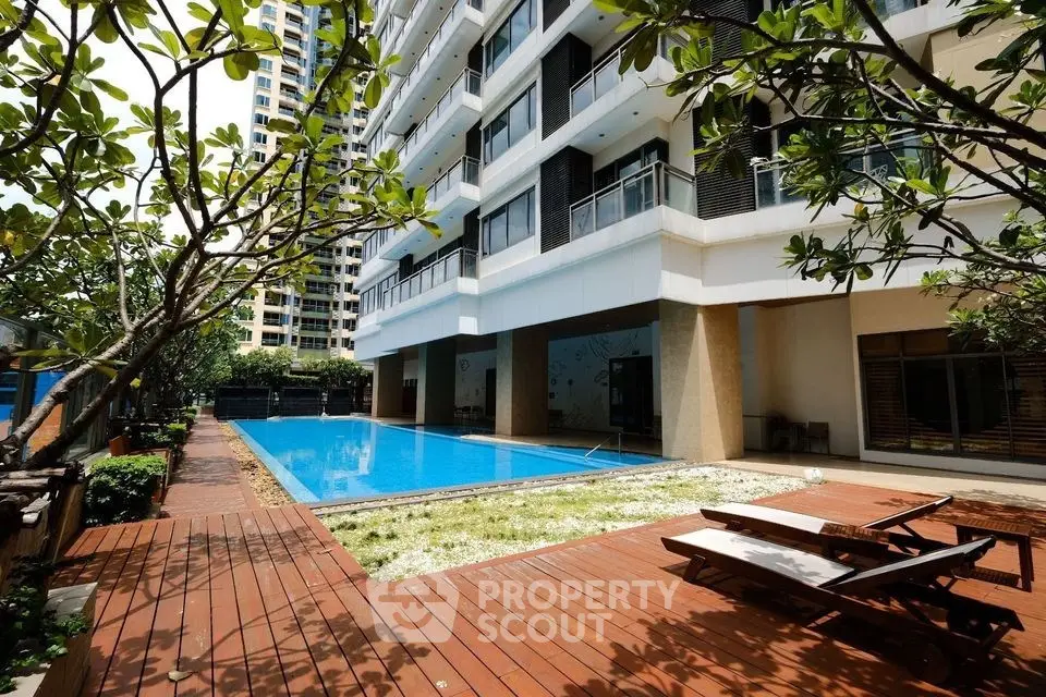 Luxurious apartment building with pool and lush greenery, perfect for relaxation and leisure.