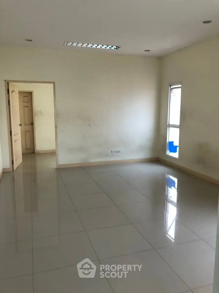 Spacious empty room with tiled flooring and natural light, ideal for customization.