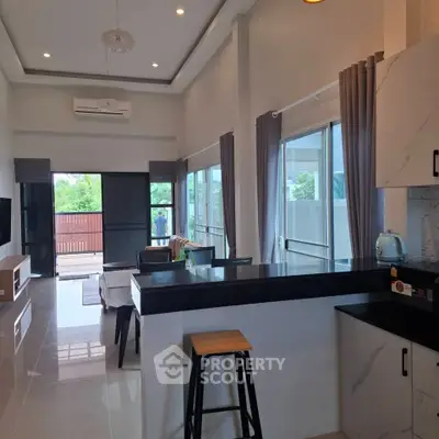 Modern open-plan living room and kitchen with large windows and stylish decor