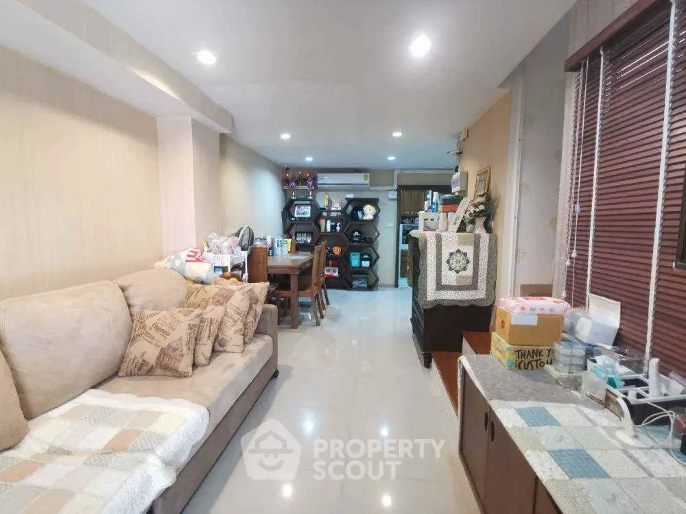 Cozy living room with beige sofa and dining area, perfect for family gatherings.