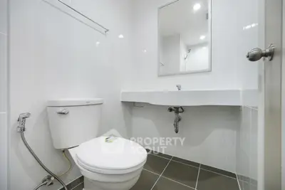 Modern bathroom with sleek white fixtures and large mirror in a minimalist design.