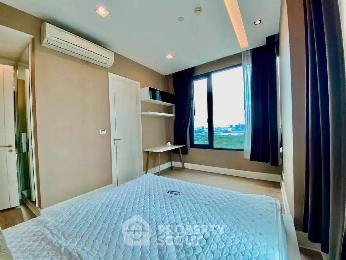 Modern bedroom with large window and city view, featuring sleek design and ample natural light.