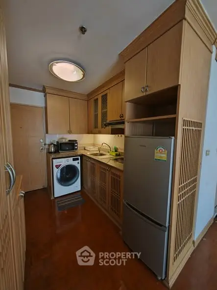 Charming compact kitchen with wooden cabinetry and modern appliances, perfect for efficient cooking in a cozy space.