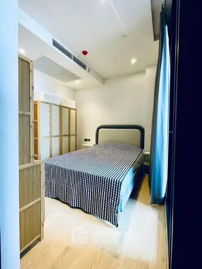 Modern bedroom with stylish decor and natural light, featuring a comfortable bed and wooden accents.