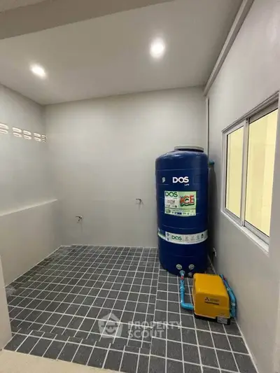 Spacious utility room with water tank and tiled flooring in modern home.