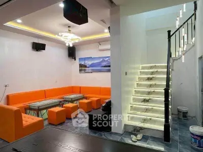 Modern living room with vibrant orange seating and illuminated staircase
