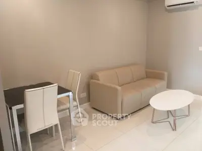 Modern living room with beige sofa, white coffee table, and dining set in a cozy apartment.
