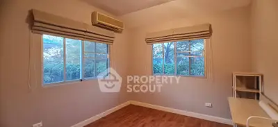 Cozy unfurnished bedroom with large windows and wooden flooring