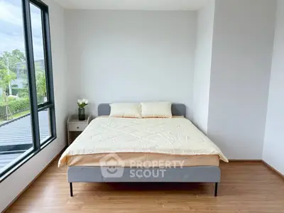 Modern bedroom with large window and cozy bed in a bright, minimalist design.