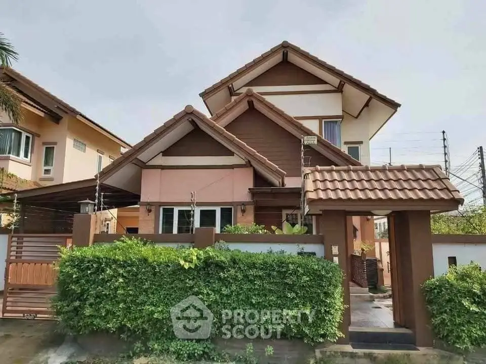 Charming two-story house with a gabled roof and lush green hedge, perfect for family living.