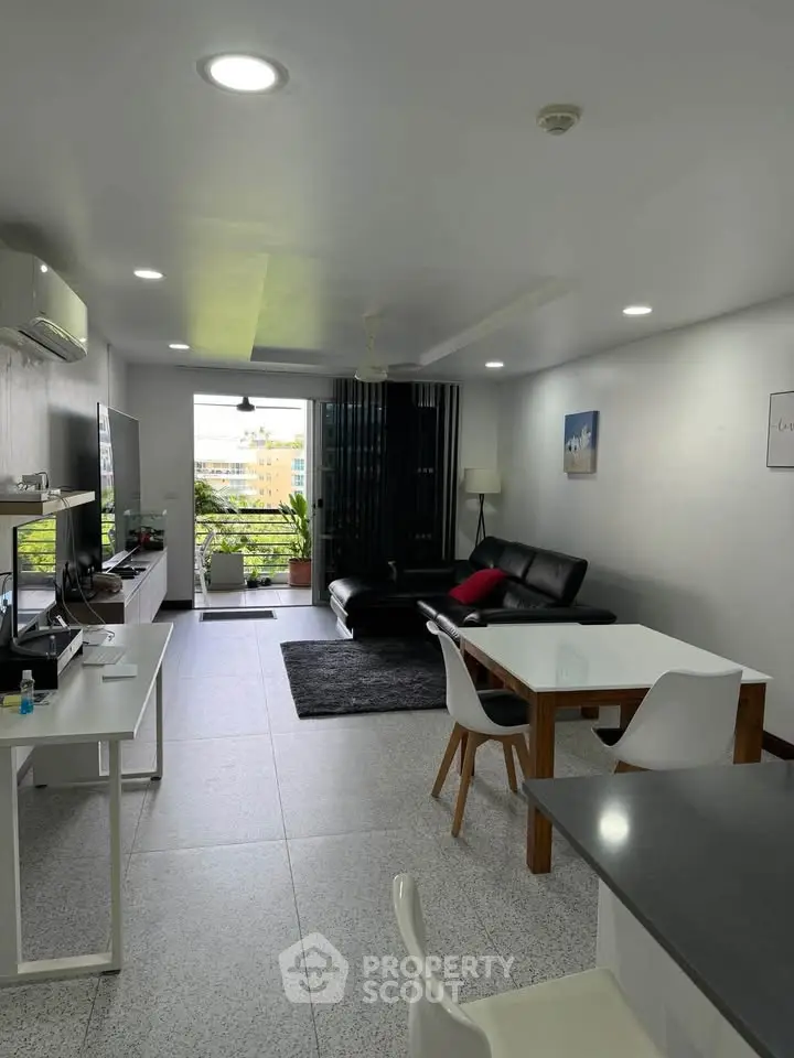 Spacious modern living room with sleek furniture and large windows offering a city view.