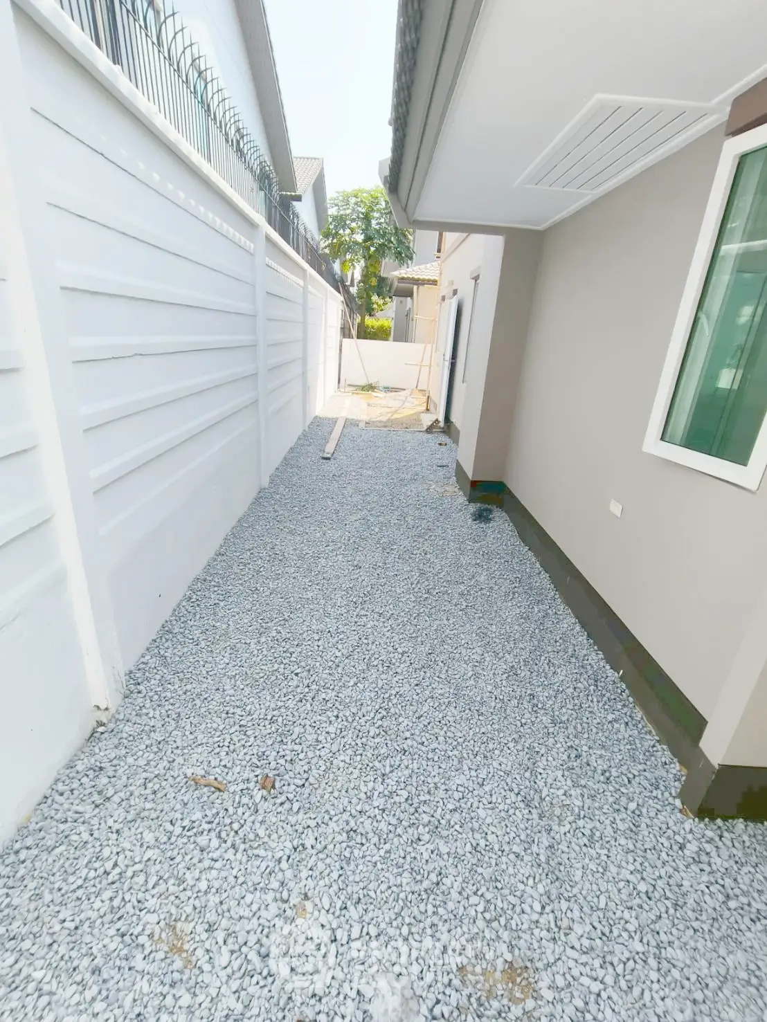 Spacious gravel side yard with modern exterior walls and secure fencing, perfect for outdoor activities.