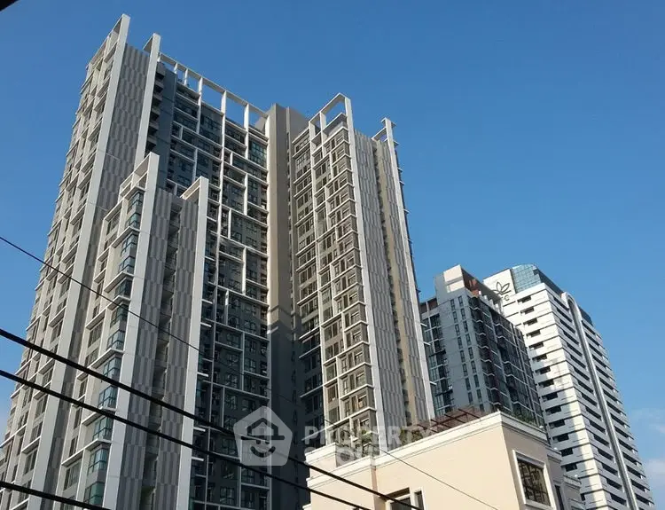 Modern high-rise residential buildings with sleek architecture against a clear blue sky.