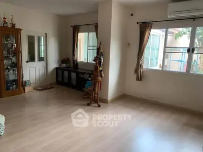 Spacious living room with wooden flooring and large windows for natural light.