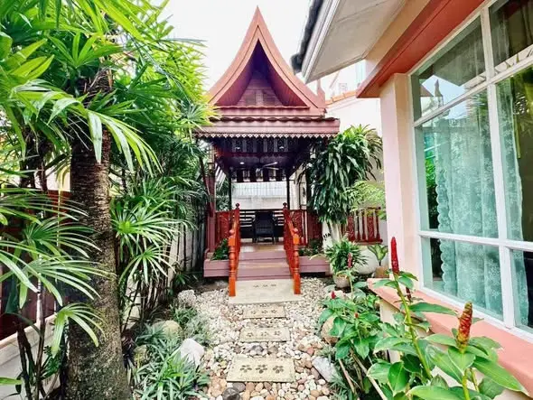 Charming Thai-style garden with traditional pavilion and lush greenery, perfect for serene outdoor living.