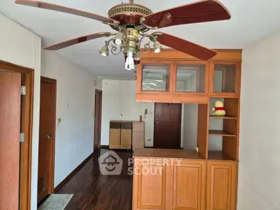 Spacious living room with wooden floors and ceiling fan, ideal for cozy gatherings.