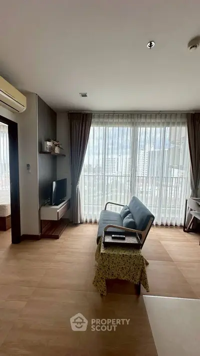 Spacious living room with modern decor and large windows offering city views.