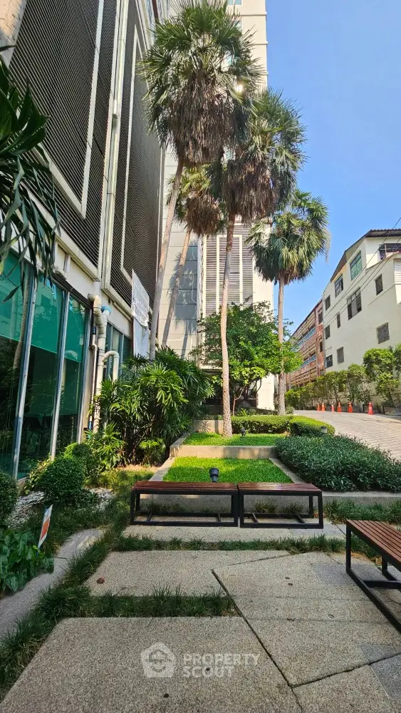 Modern building exterior with lush landscaping and tall palm trees
