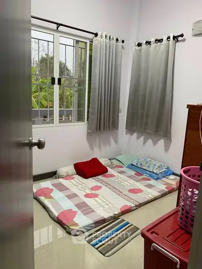 Cozy bedroom with floor mattress and natural light from window.