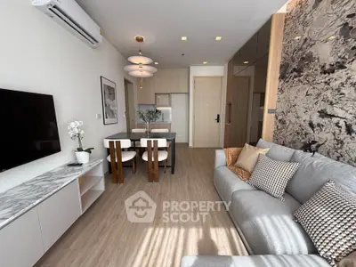 Modern living room with stylish decor and open dining area, featuring elegant lighting and a cozy ambiance.