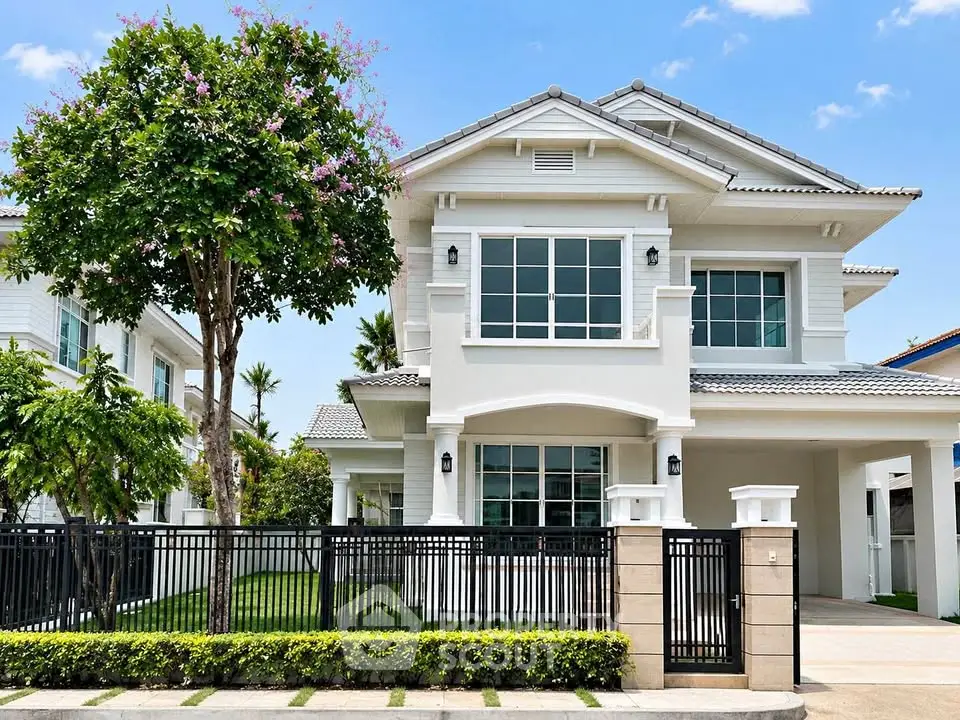 Stunning two-story white house with lush garden and modern architecture in a serene neighborhood.