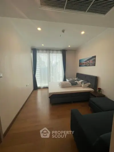 Spacious bedroom with modern decor and large window offering natural light.