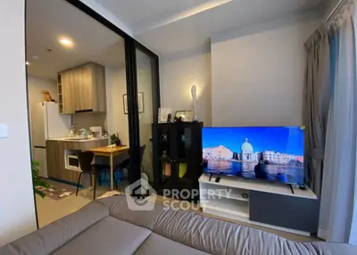 Modern living room with open kitchen, sleek furniture, and large TV, perfect for urban living.