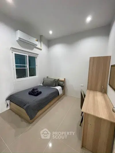 Modern bedroom with sleek design, featuring a comfortable bed, study desk, and air conditioning.
