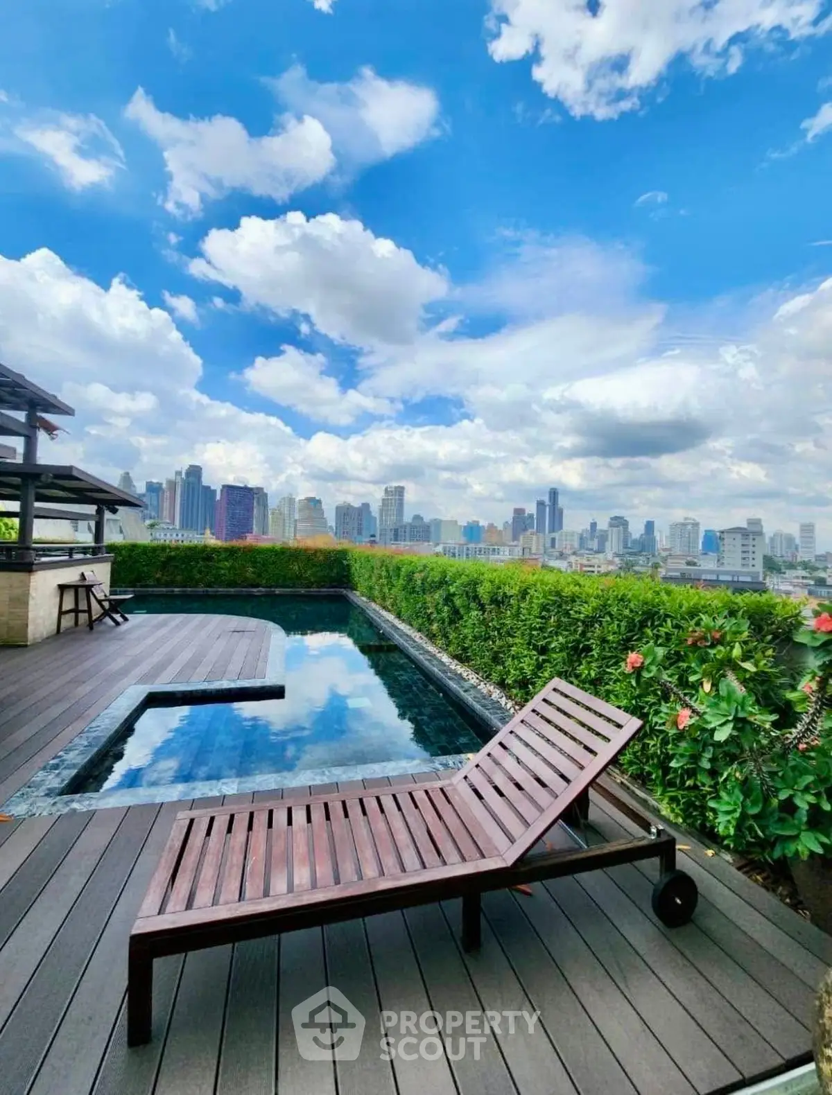 Luxurious rooftop pool with stunning city skyline view and elegant wooden deck.