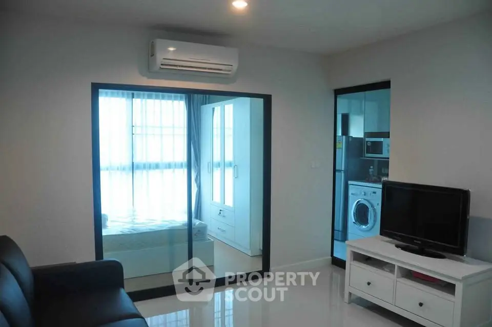 Modern apartment interior with sleek living room and bedroom view, featuring air conditioning and stylish furniture.