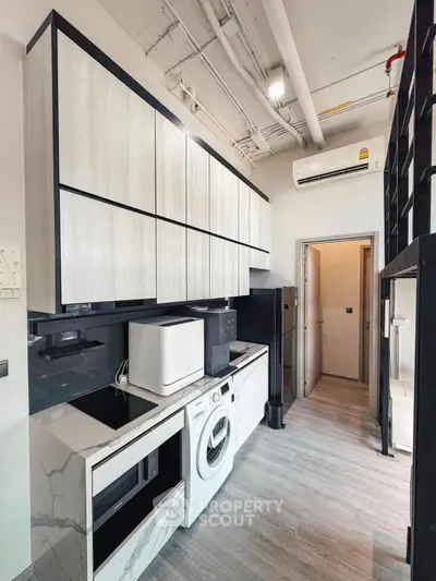 Modern kitchen with sleek cabinetry, washing machine, and microwave in compact layout.