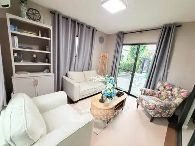 Charming living room with elegant decor and garden view, featuring cozy sofas and floral armchair.