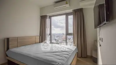Modern bedroom with city view, featuring large window and sleek furnishings.