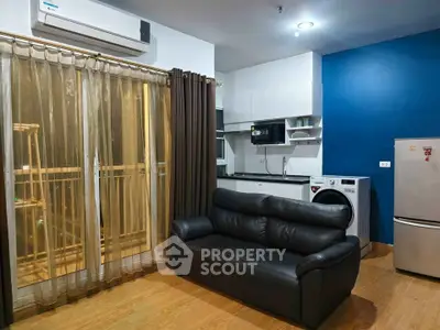 Modern living room with sleek black sofa, integrated kitchen, and balcony access in stylish apartment.