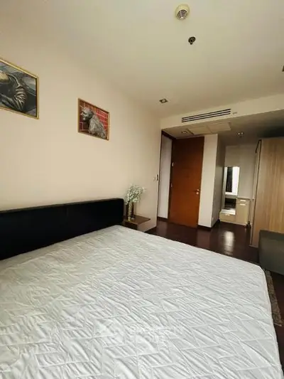 Spacious bedroom with modern decor and ample natural light, featuring a large bed and stylish artwork.