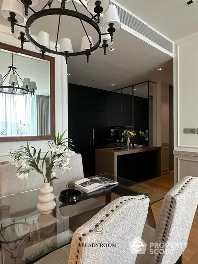 Elegant open-plan living space with a sleek black kitchen and a stylish dining area, accented by chic lighting fixtures and tasteful decor.