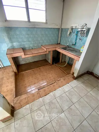 Basic kitchen with tiled countertops and sink in need of renovation.