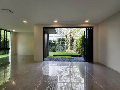 Spacious modern living room with large glass doors opening to a lush garden view.