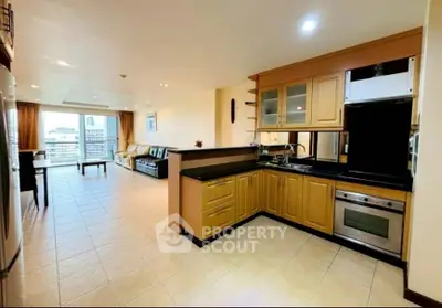 Spacious open-plan living room with modern kitchen and balcony view.