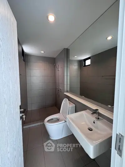 Modern bathroom with sleek fixtures and large mirror in contemporary home.