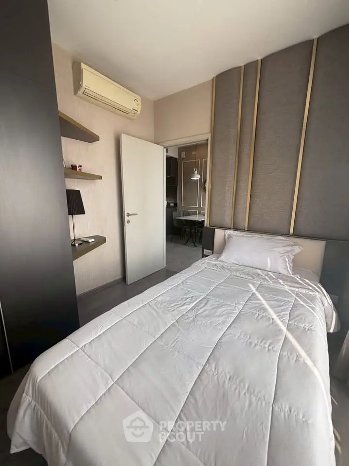 Modern bedroom with sleek design and air conditioning, featuring a cozy single bed and stylish wall paneling.