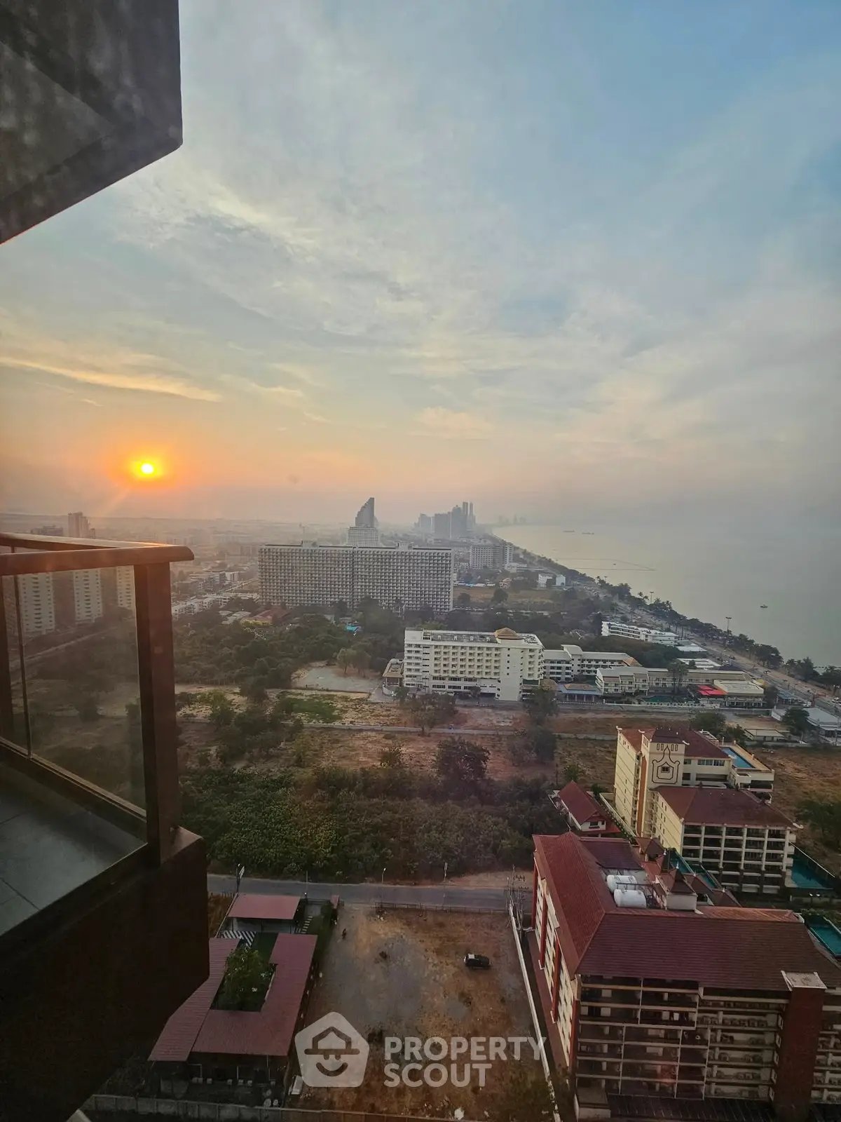 Stunning high-rise view of cityscape and ocean at sunset, perfect for luxury living.