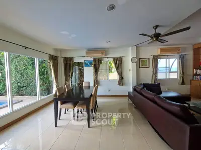 Spacious living room with modern furniture and large windows overlooking greenery.