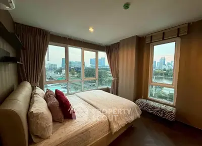 Spacious bedroom with large windows offering stunning city views, perfect for urban living.