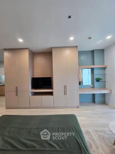 Modern bedroom with built-in wardrobe and TV unit, featuring sleek design and ample storage space.
